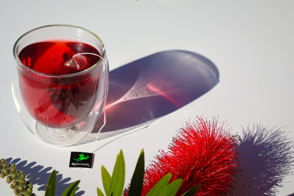 Roogenics red detox tea in glass cup with red reflection